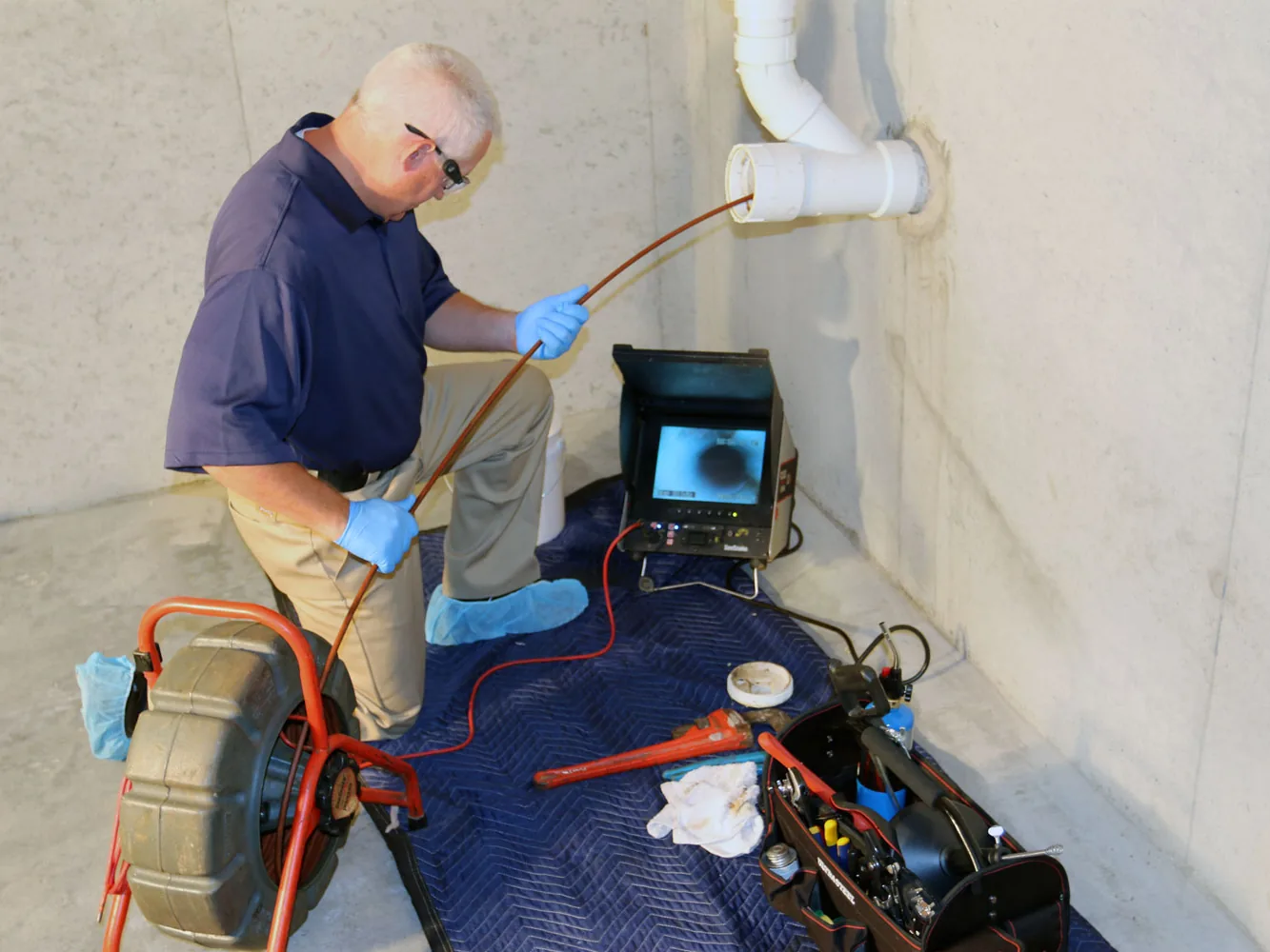 Drain cleaning camera inspection fed through a cleanout with the monitor beside it