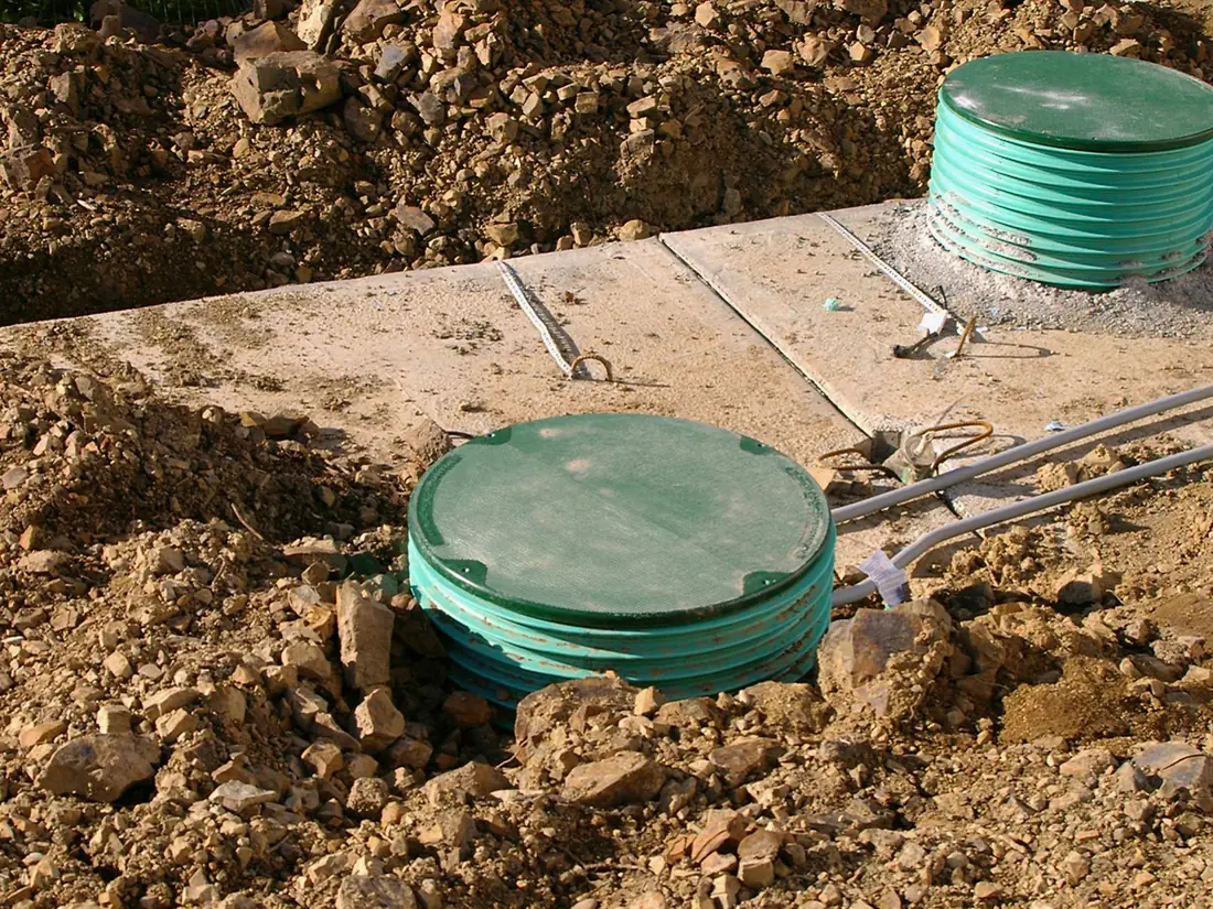 Drain cleaning access with septic tank lids raised to grade on green risers