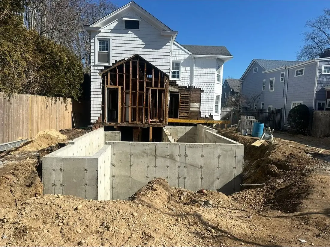Excavation for a home addition with a new poured foundation standing in the open dig