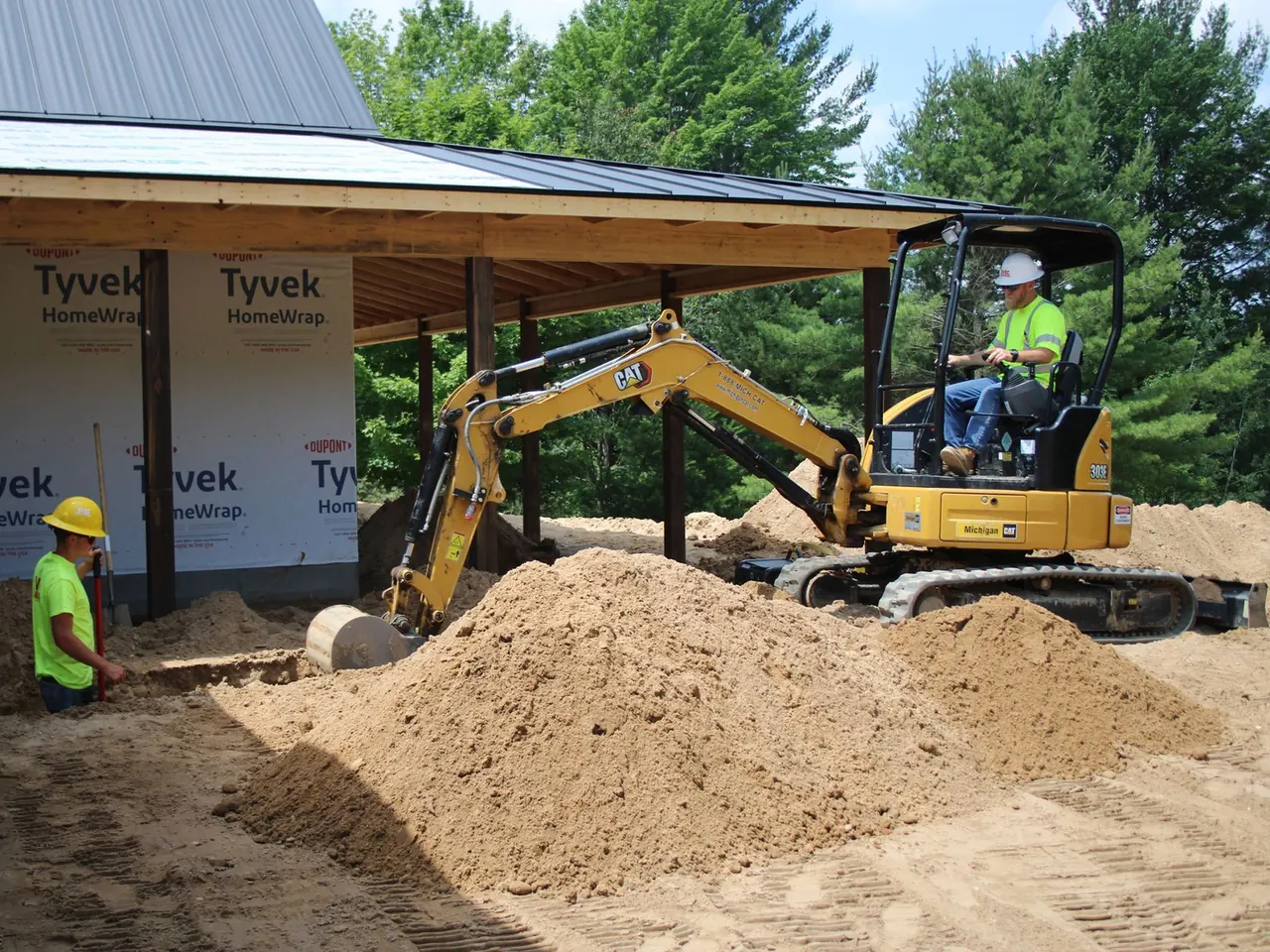 Excavation with a mini excavator digging a trench beside a new building