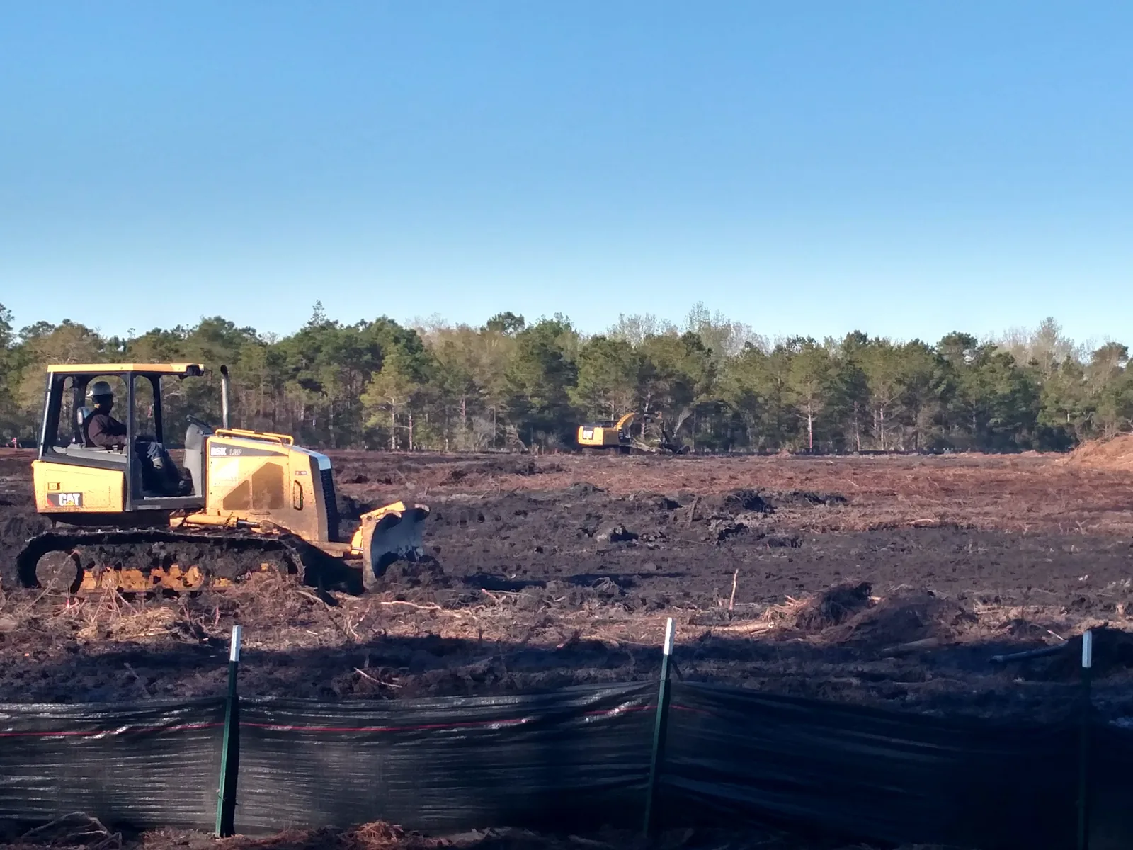 Site work with a dozer clearing and grading a lot behind a silt fence