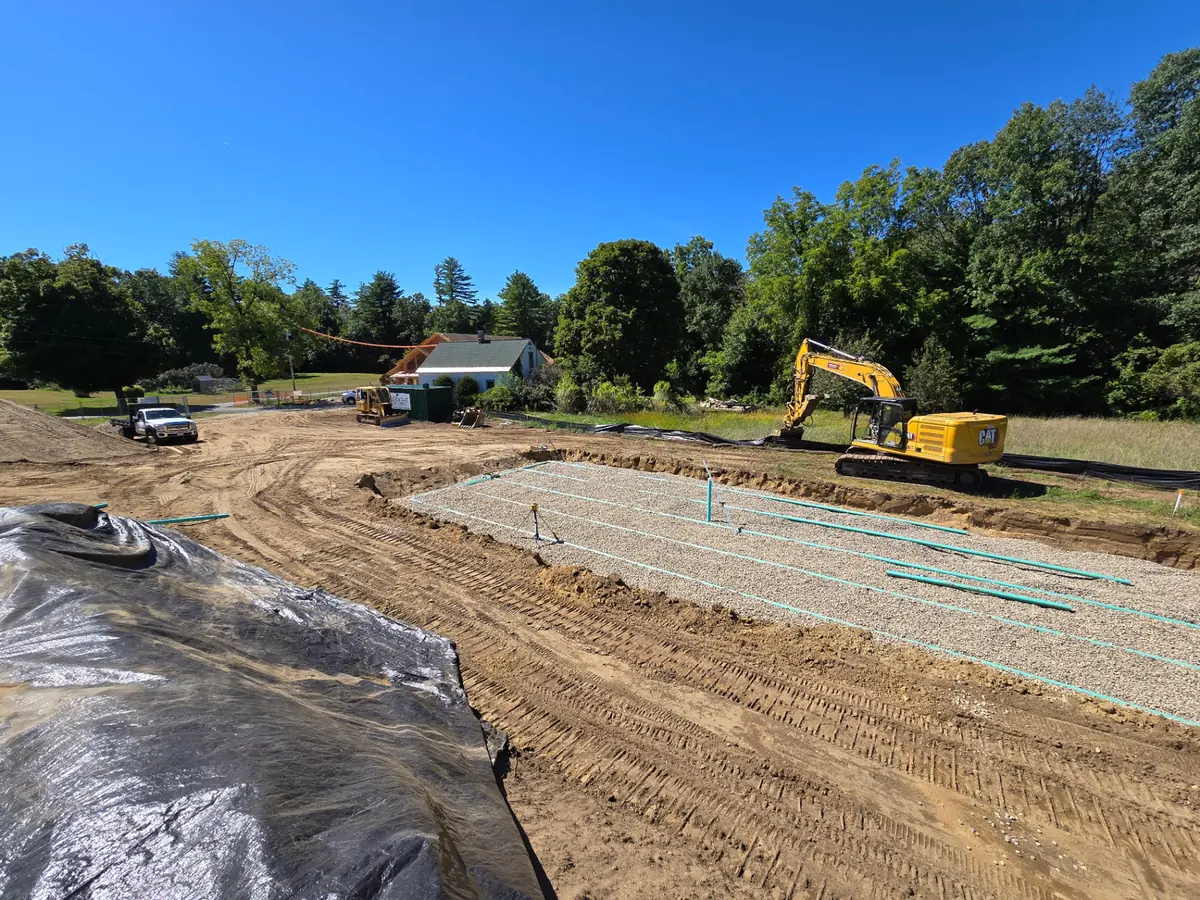 Excavator beside a long dug bed with new pipe laid out, water line repair